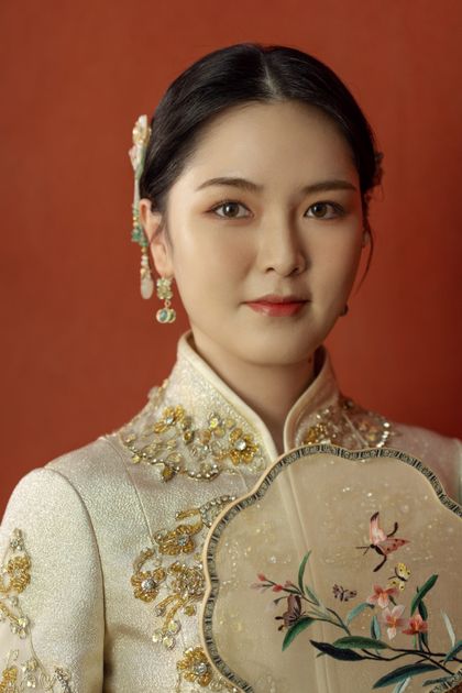 Portrait of a woman in traditional Chinese attire holding a decorative fan, demonstrating how Chinese floral embroidery creates a complete visual language in contemporary styling.