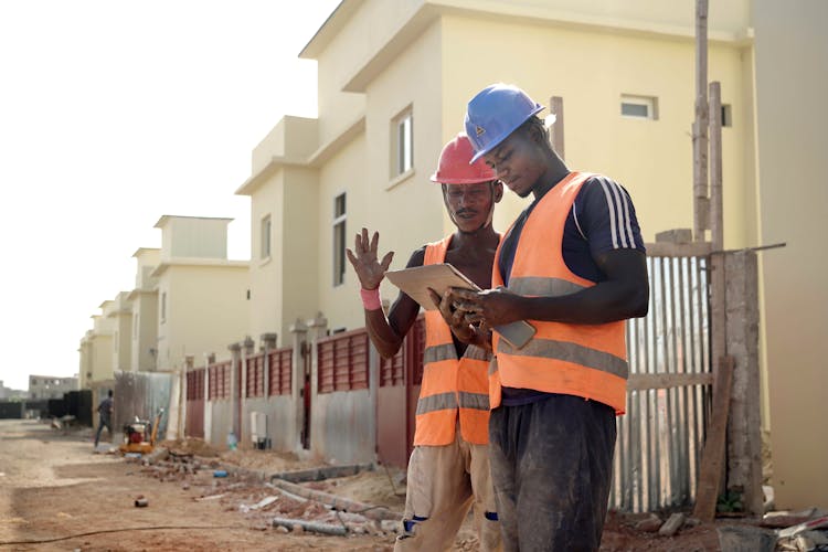 Construction Workers In Helmets And Reflective Vests