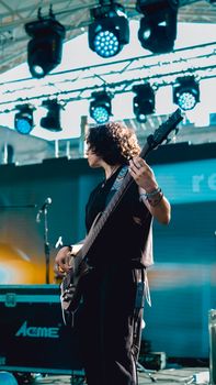 A captivating image of a musician performing with a bass guitar at an outdoor concert.