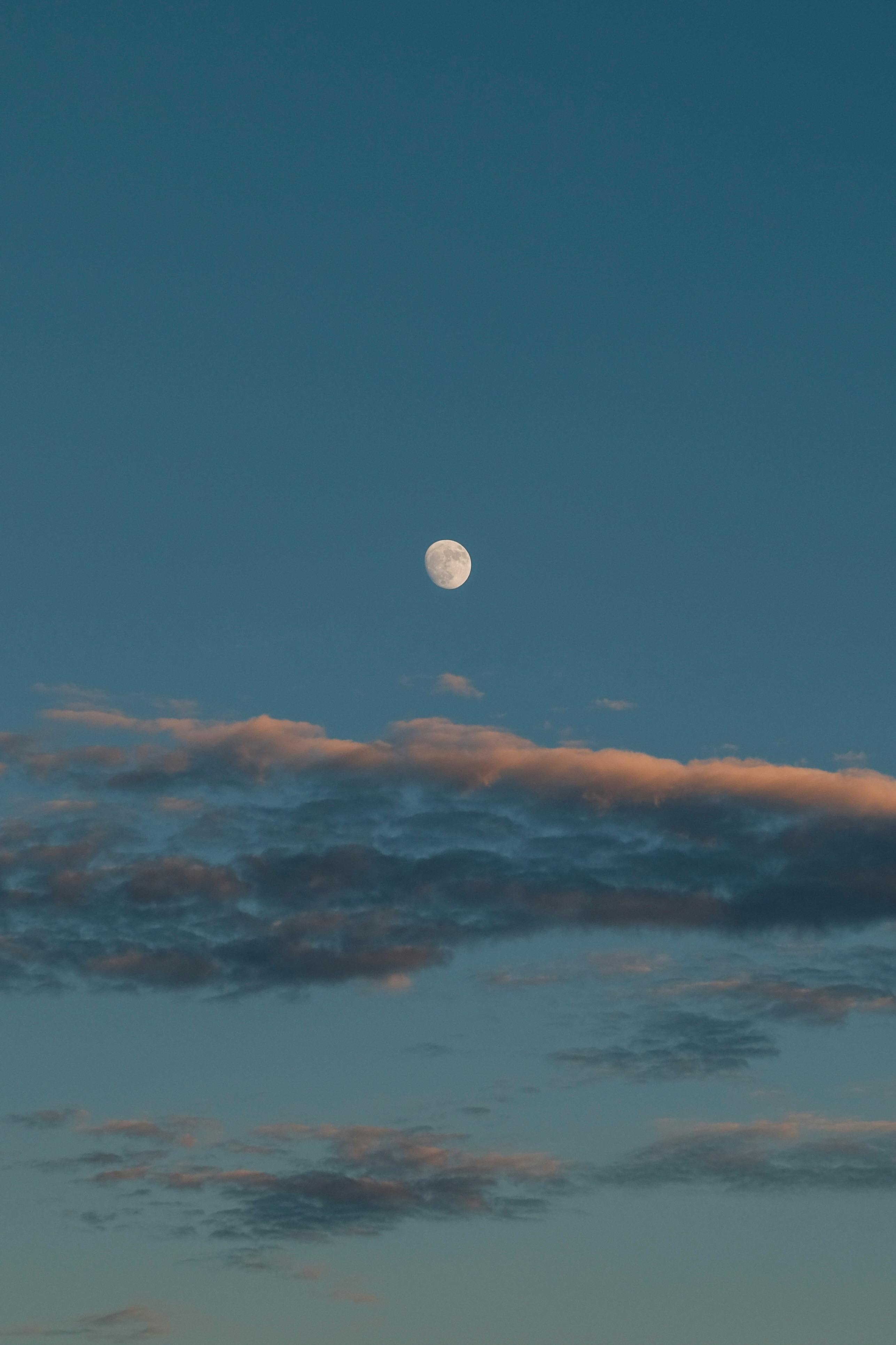 Enchanting dusk scene featuring a luminous moon surrounded by delicate clouds in a serene sky.