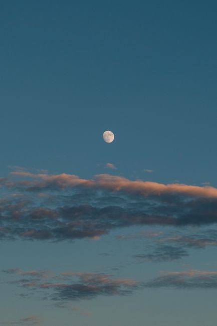 Enchanting dusk scene featuring a luminous moon surrounded by delicate clouds in a serene sky.