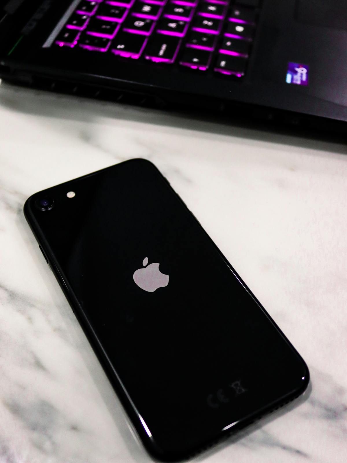 Primo piano di uno smartphone appoggiato accanto a un laptop aperto
