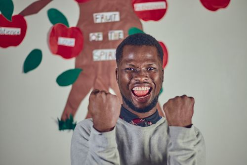 Free Excited man expressing joy with fists raised indoors, showcasing happiness and success. Stock Photo