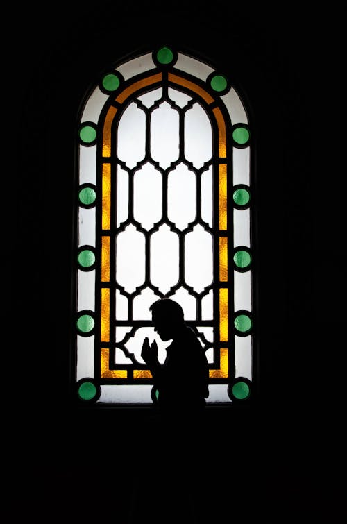 Silhouette of a Man in front of Stained Glass Window