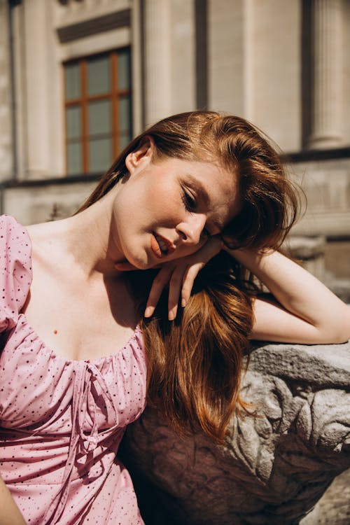 Young Woman in a Pink Dress Sitting Outside in Sunlight 