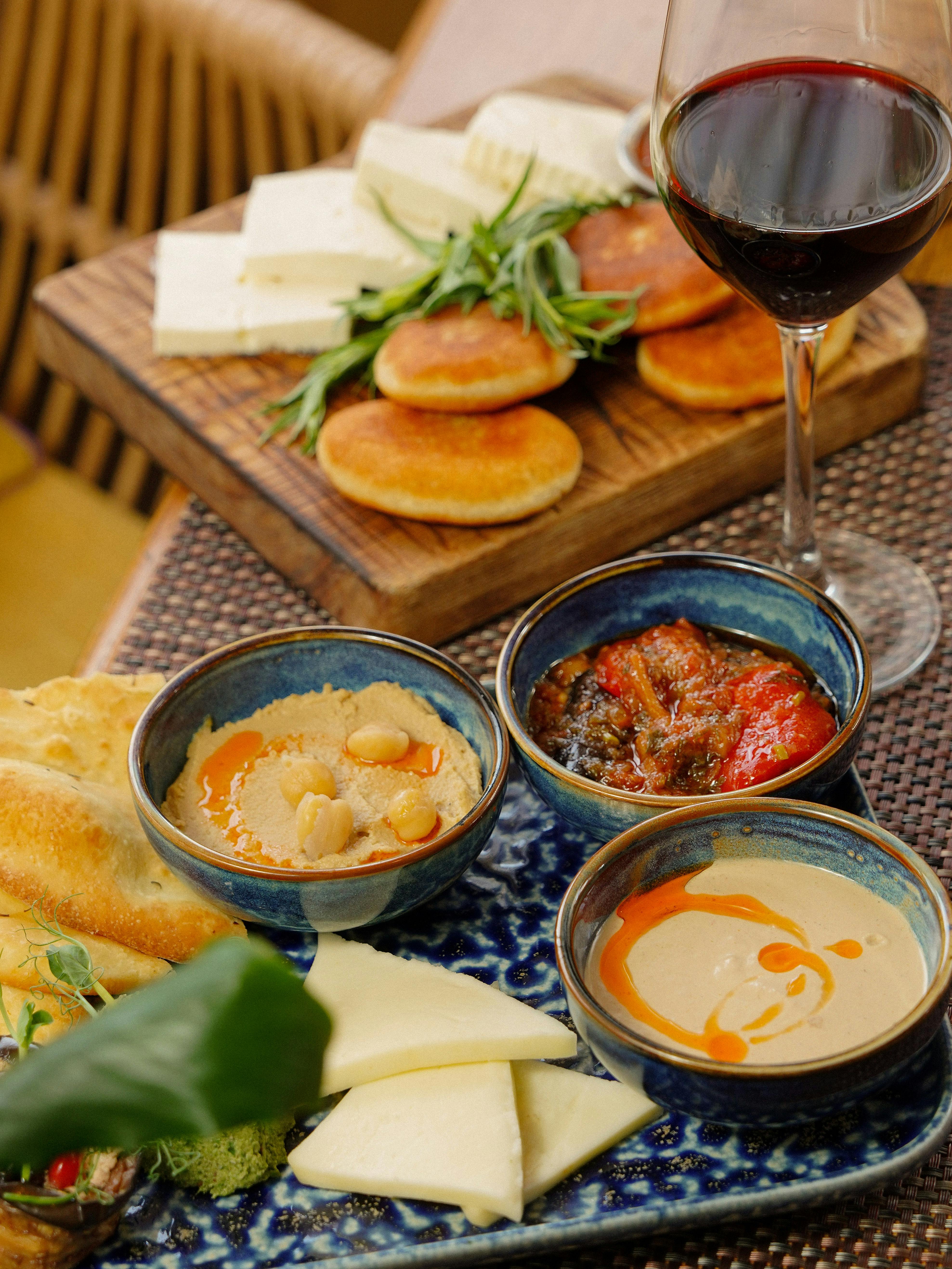 A gourmet spread of appetizers including hummus, cheese, and wine for a culinary experience.