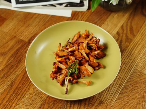 A mouthwatering serving of fried chanterelle mushrooms beautifully plated on a wooden table.