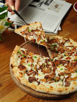 A scrumptious cheese and mushroom pizza slice being served from a wooden board.