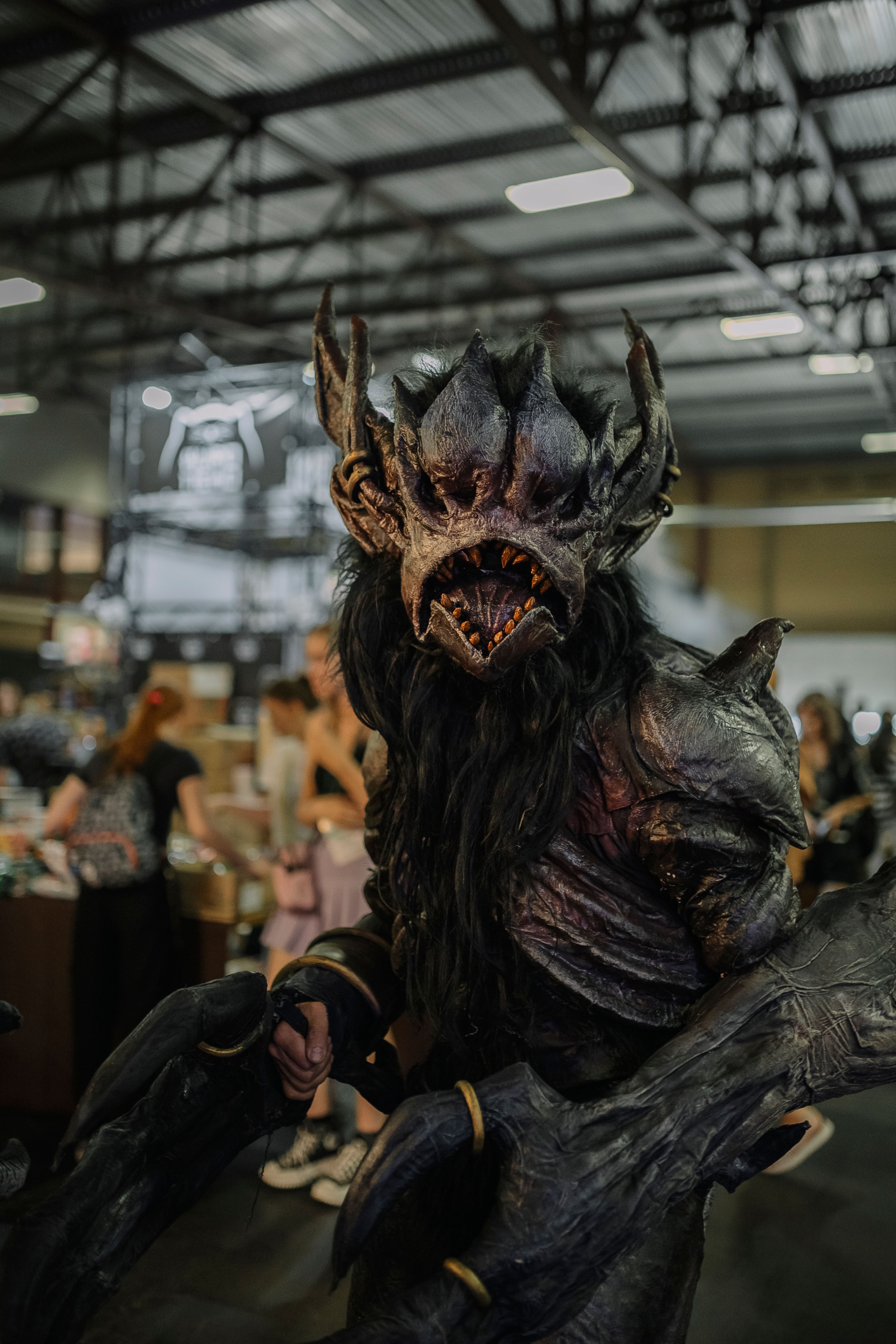 A stunning cosplay of a ferocious creature at a bustling convention event.