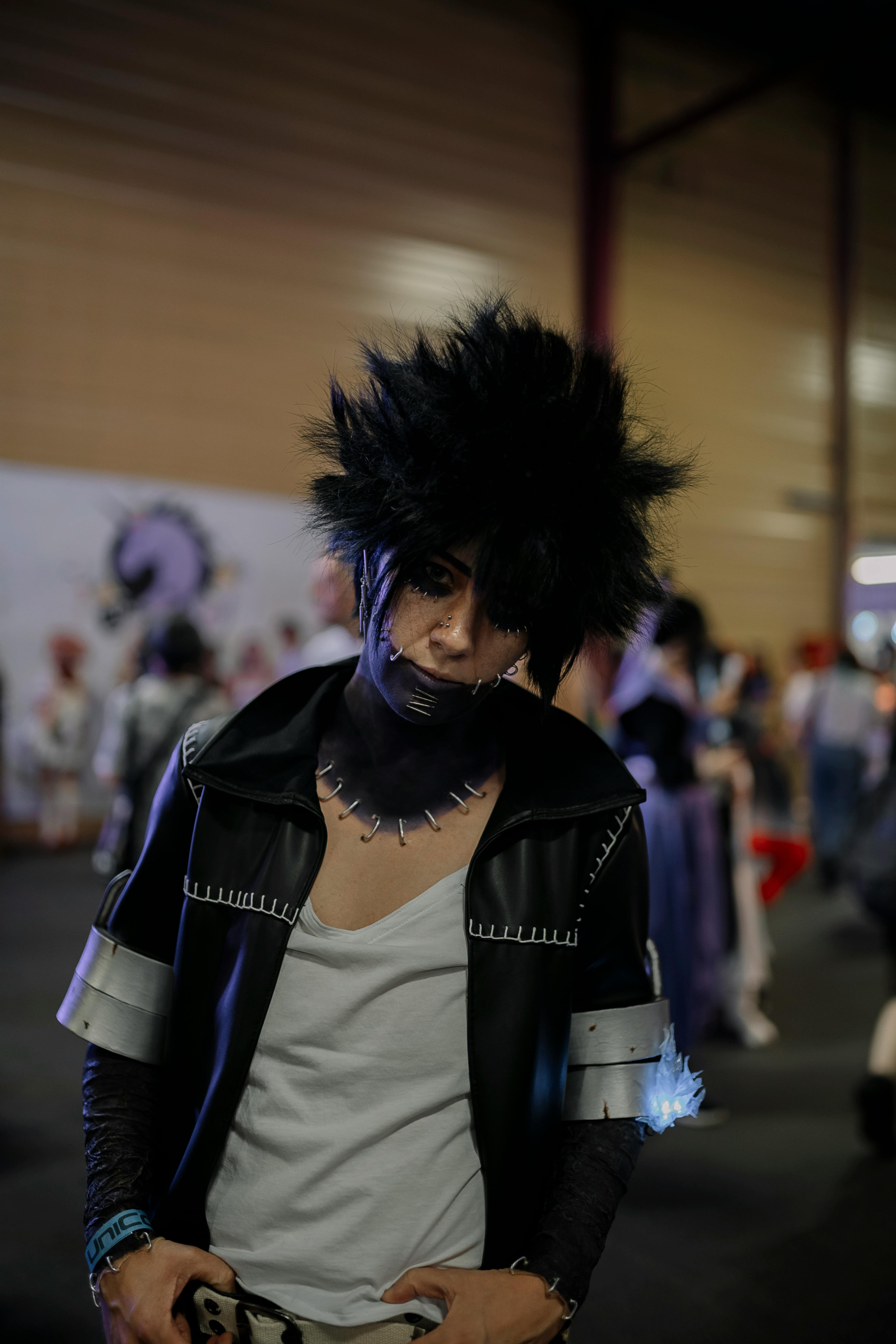 Vibrant cosplay character at a convention showcasing dramatic hairstyle and unique makeup.