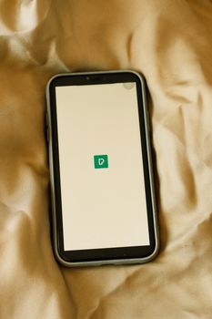 A smartphone placed on a bed, displaying a simple app screen with a minimal design