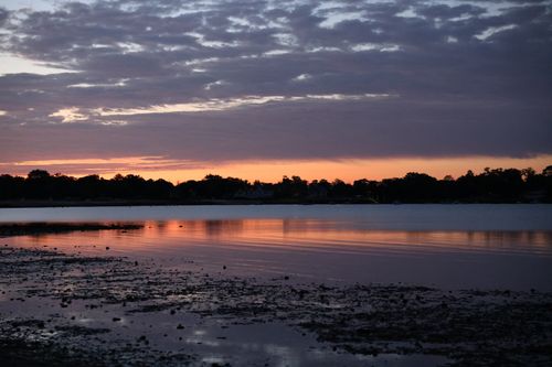 Free Capture of a peaceful sunset over a calm lake with reflected clouds, creating a soothing ambiance. Stock Photo