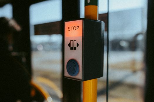 A close-up of a stop button on a public bus, highlighting travel and safety features.