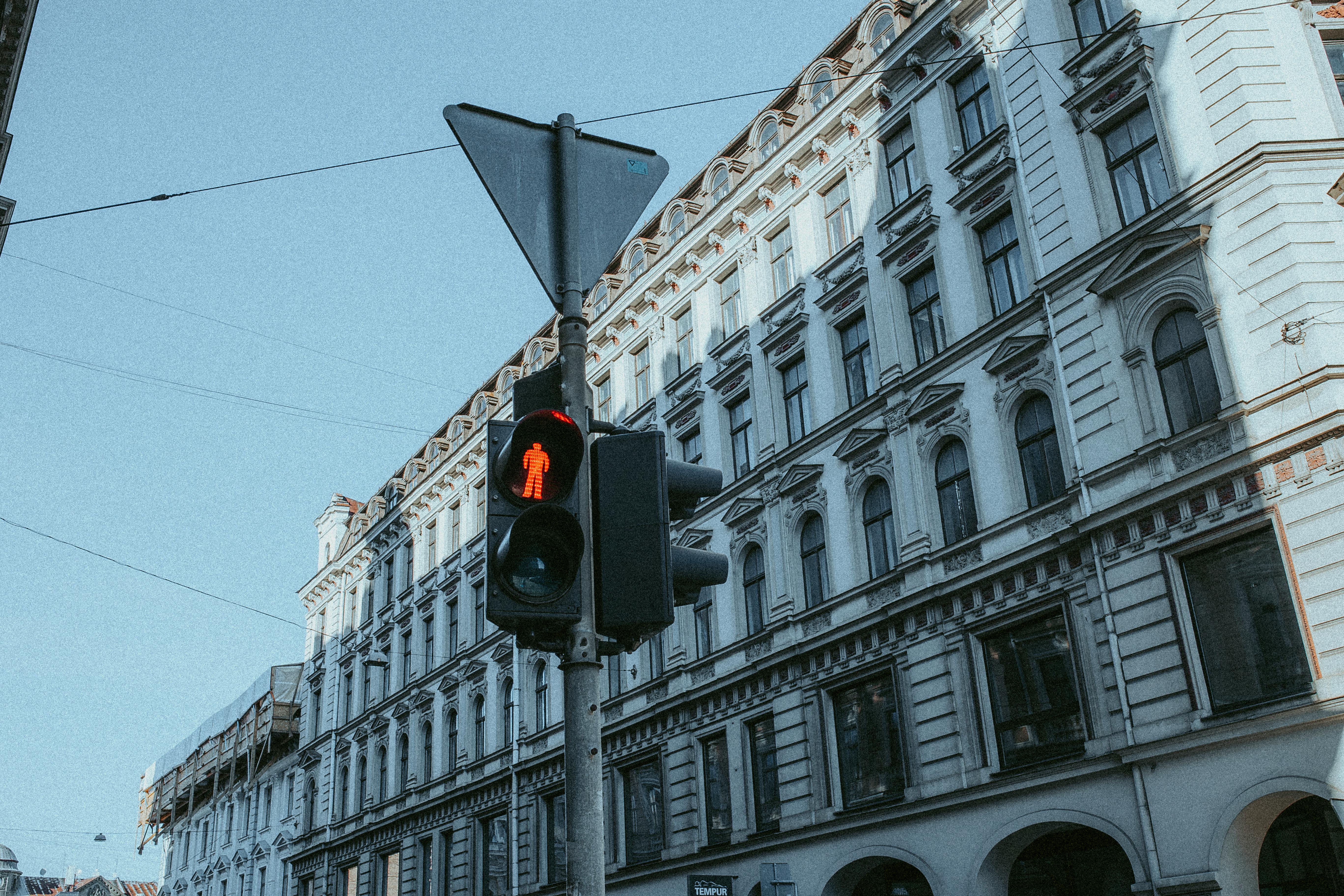 Street view of a red traffic light against a classic building facade in an urban setting.