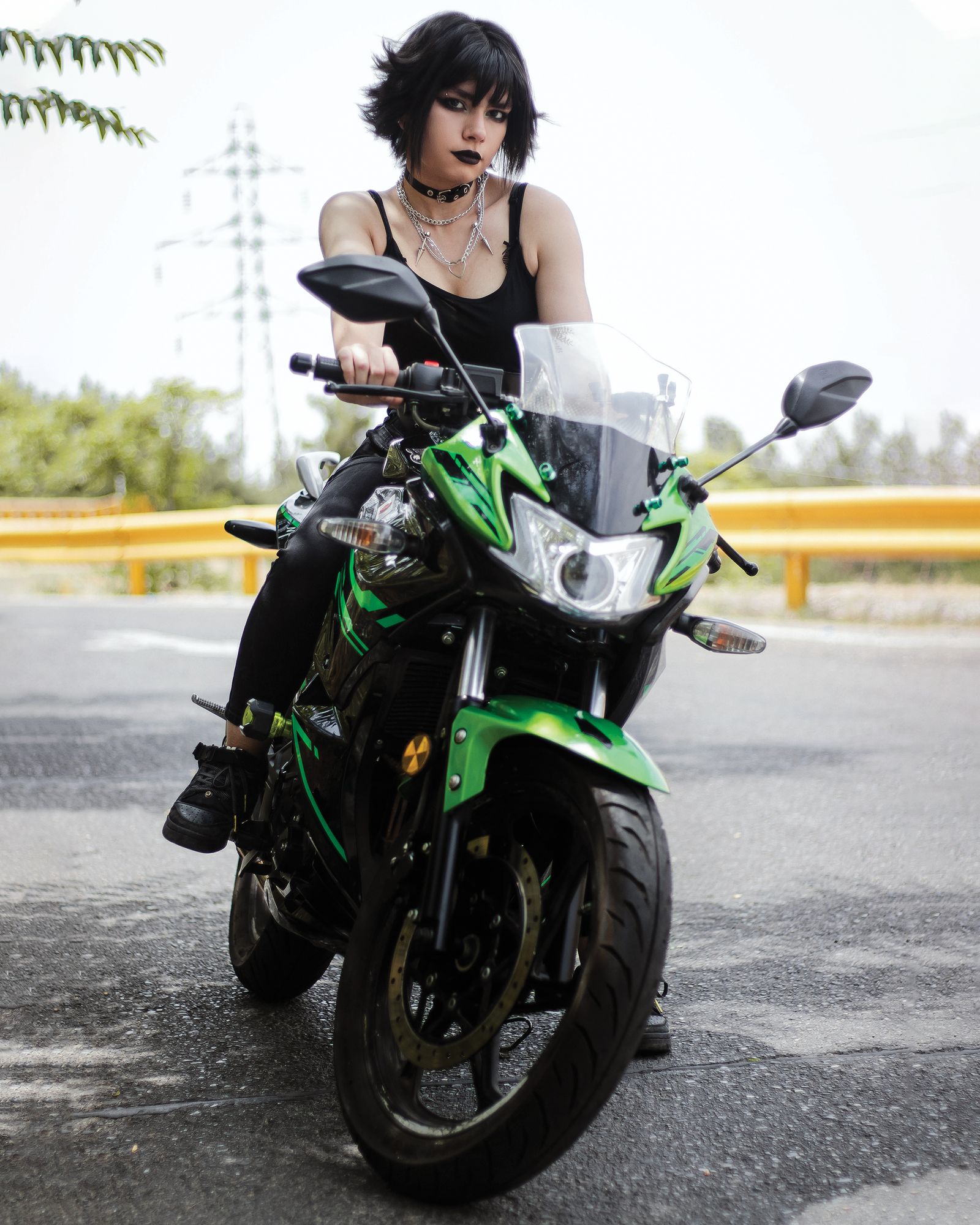 Femme posant sur une moto Kawasaki Z900 verte sur une route de campagne