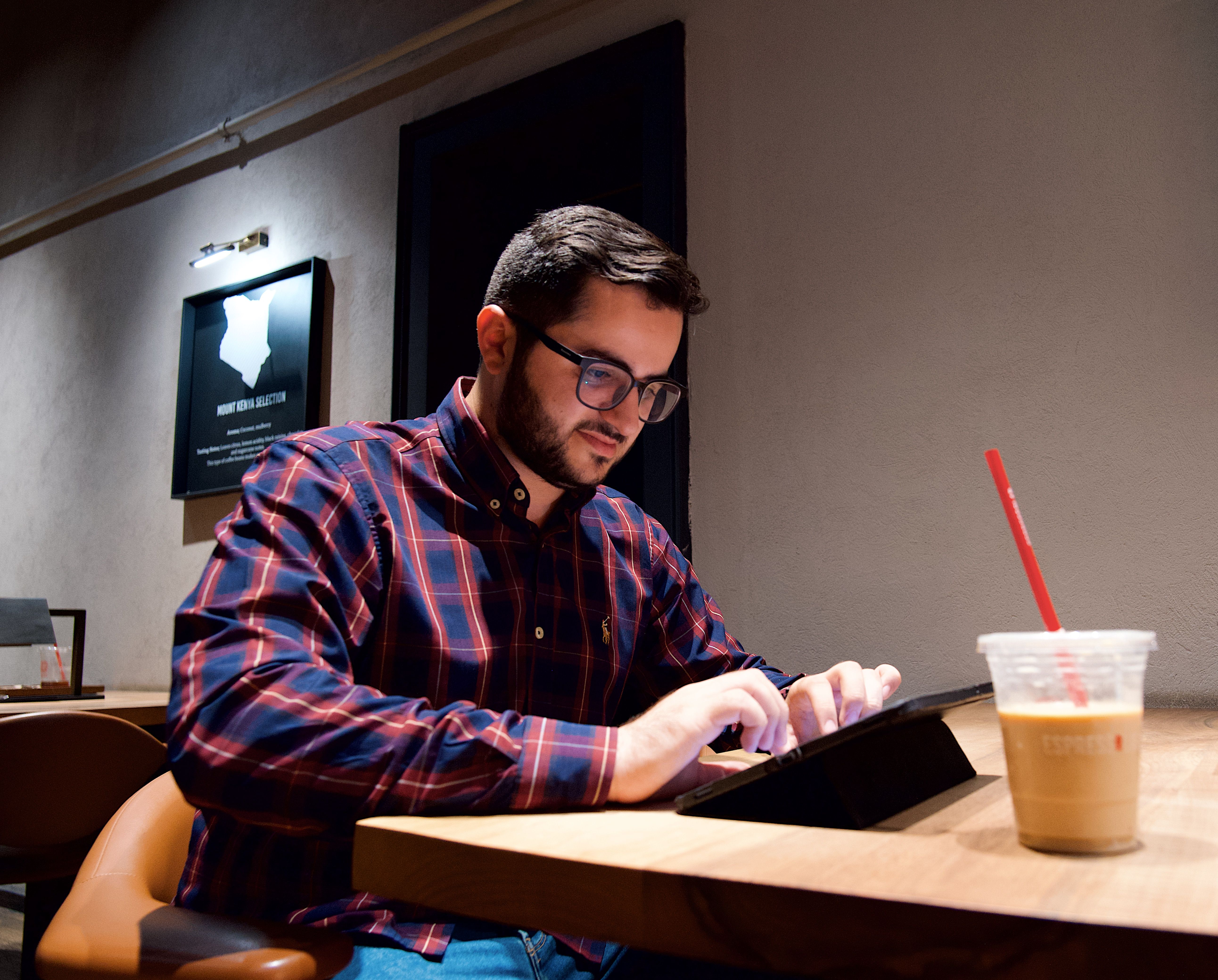 Person in a coffee shop working on financial calculations with a tablet