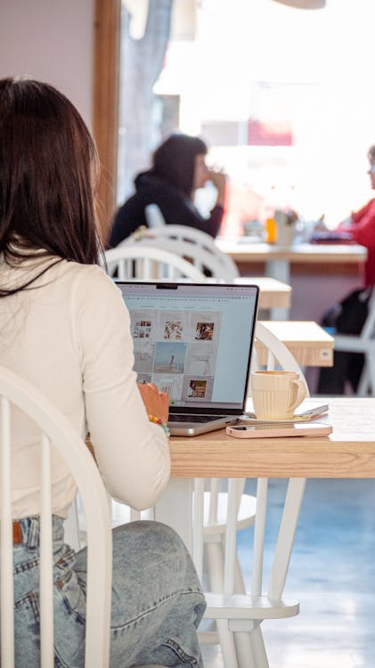 Woman Sits at Table in Cafe with Laptop