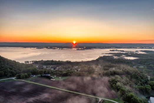 Stunning aerial view of Weaver, MN with vibrant sunset over lush landscape and serene river.