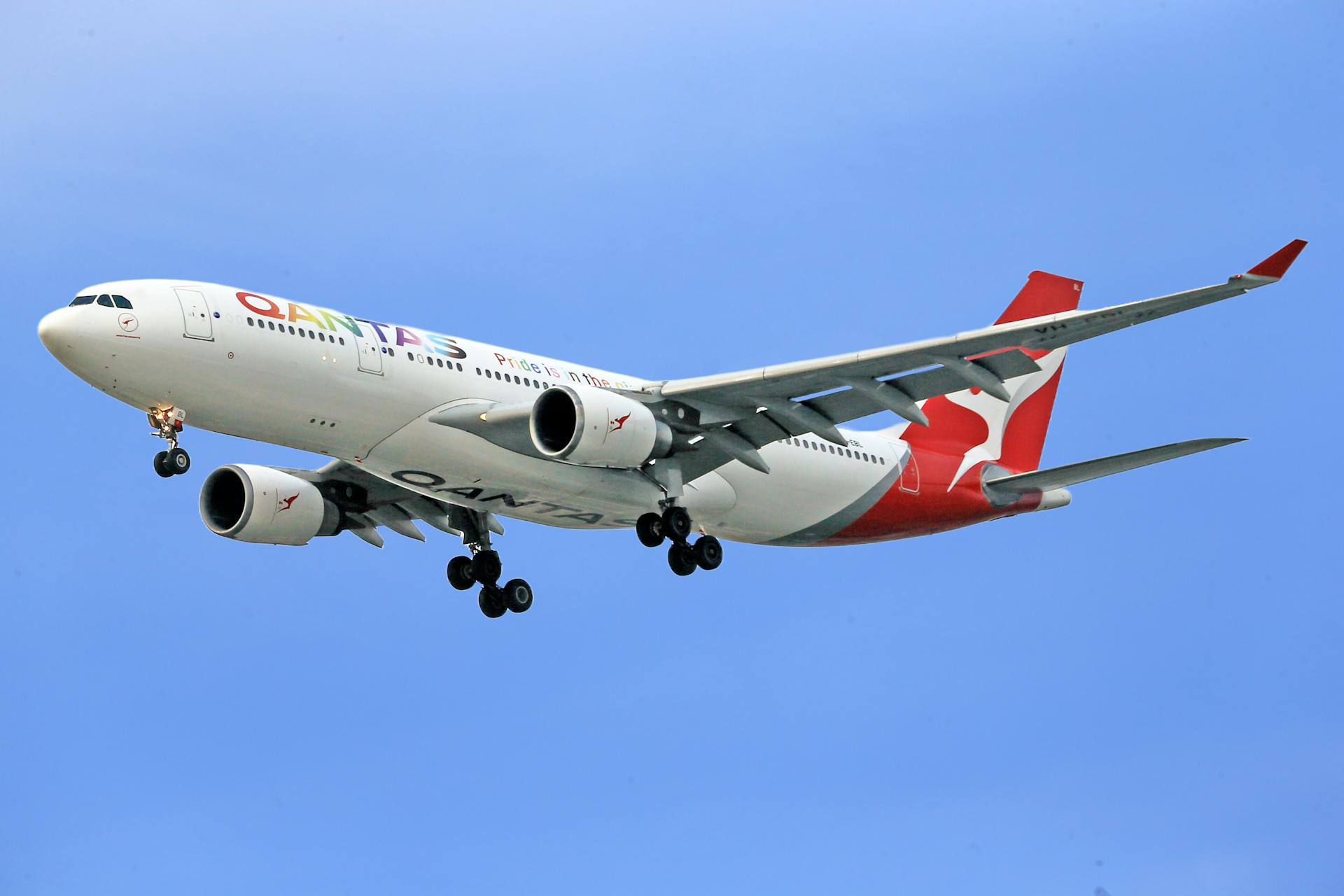 A Qantas Airbus A330 jetliner in flight against a clear blue sky, showcasing aviation elegance.