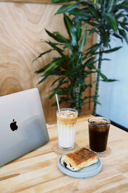 Cozy cafe scene with iced coffee, pastry, and laptop, ideal for work or relaxation.