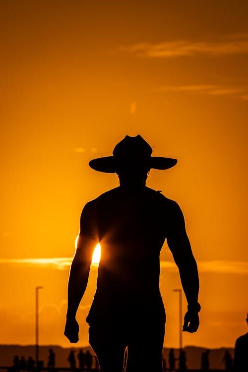 Muscular Man in Hat at Sunset