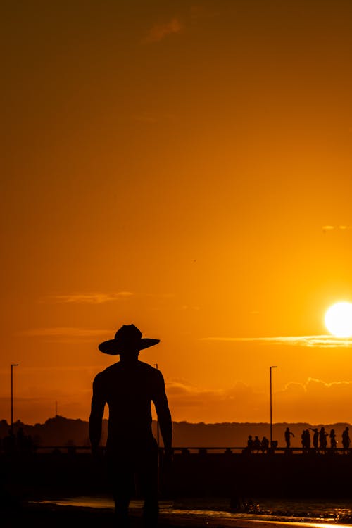 Man in Hat Stands at Sunset