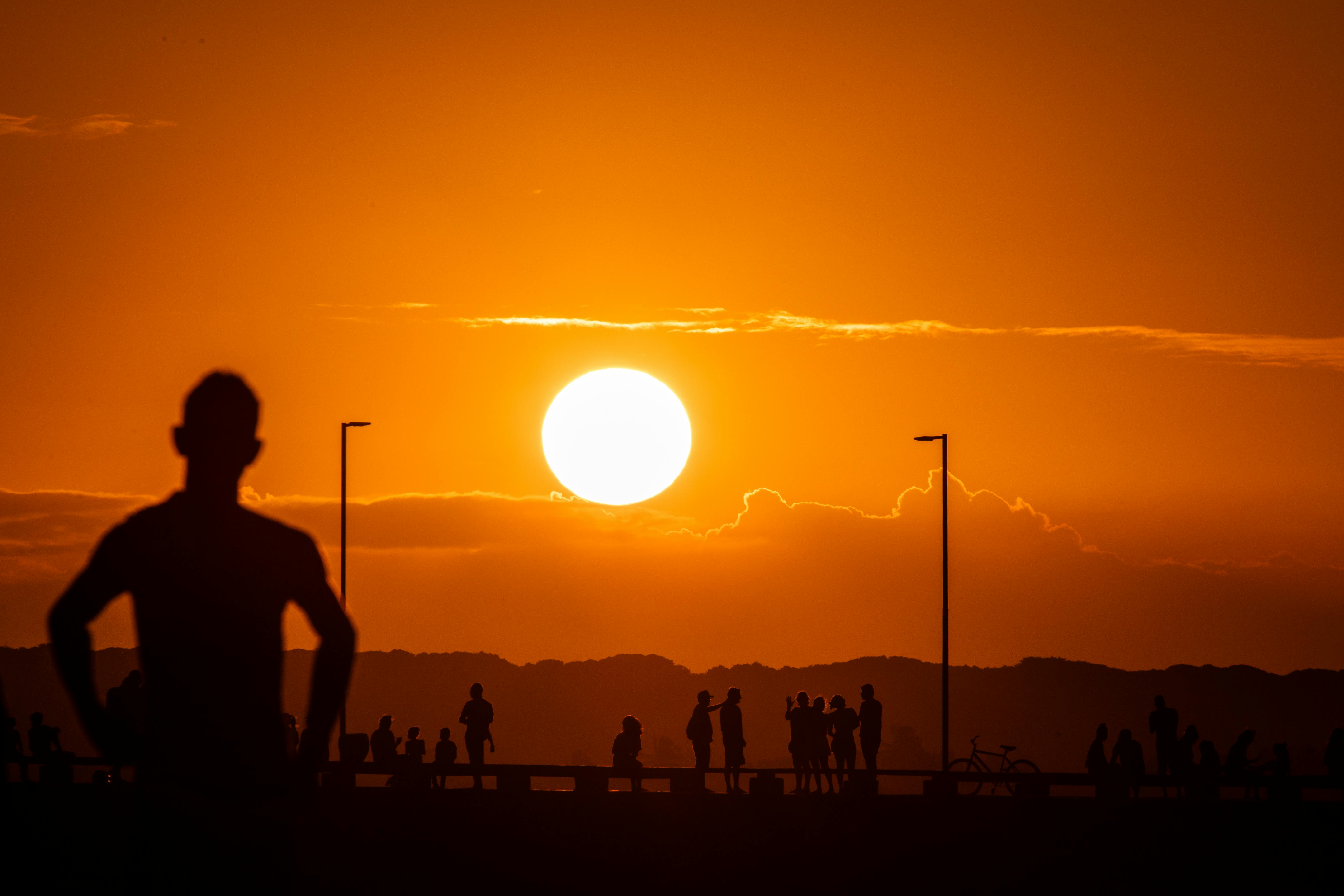Silhouettes against a vibrant sunset in Cabedelo, Brazil, showcasing a scenic ocean horizon.