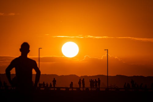 Sun on Yellow Sky at Sunset over People Silhouette