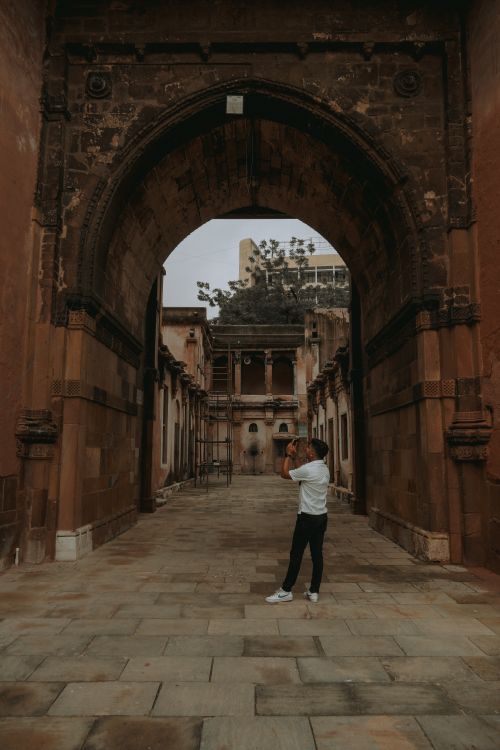 Free A traveler photographs ancient architecture in Ahmedabad's urban streets. Stock Photo