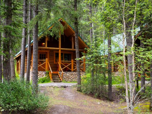 Free Charming wooden cabin nestled among trees, ideal for a serene forest retreat. Stock Photo