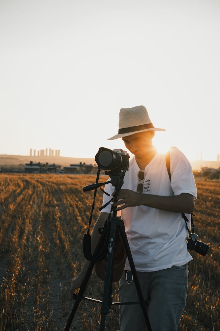 Man Adjusting Digital Camera On Stand At Sunrise