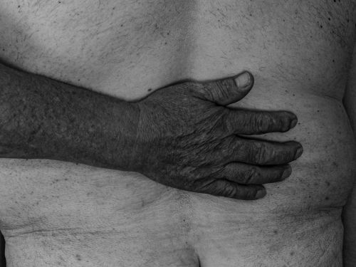 Free A black and white close-up of a hand touching a person's back, symbolizing intimacy and connection. Stock Photo
