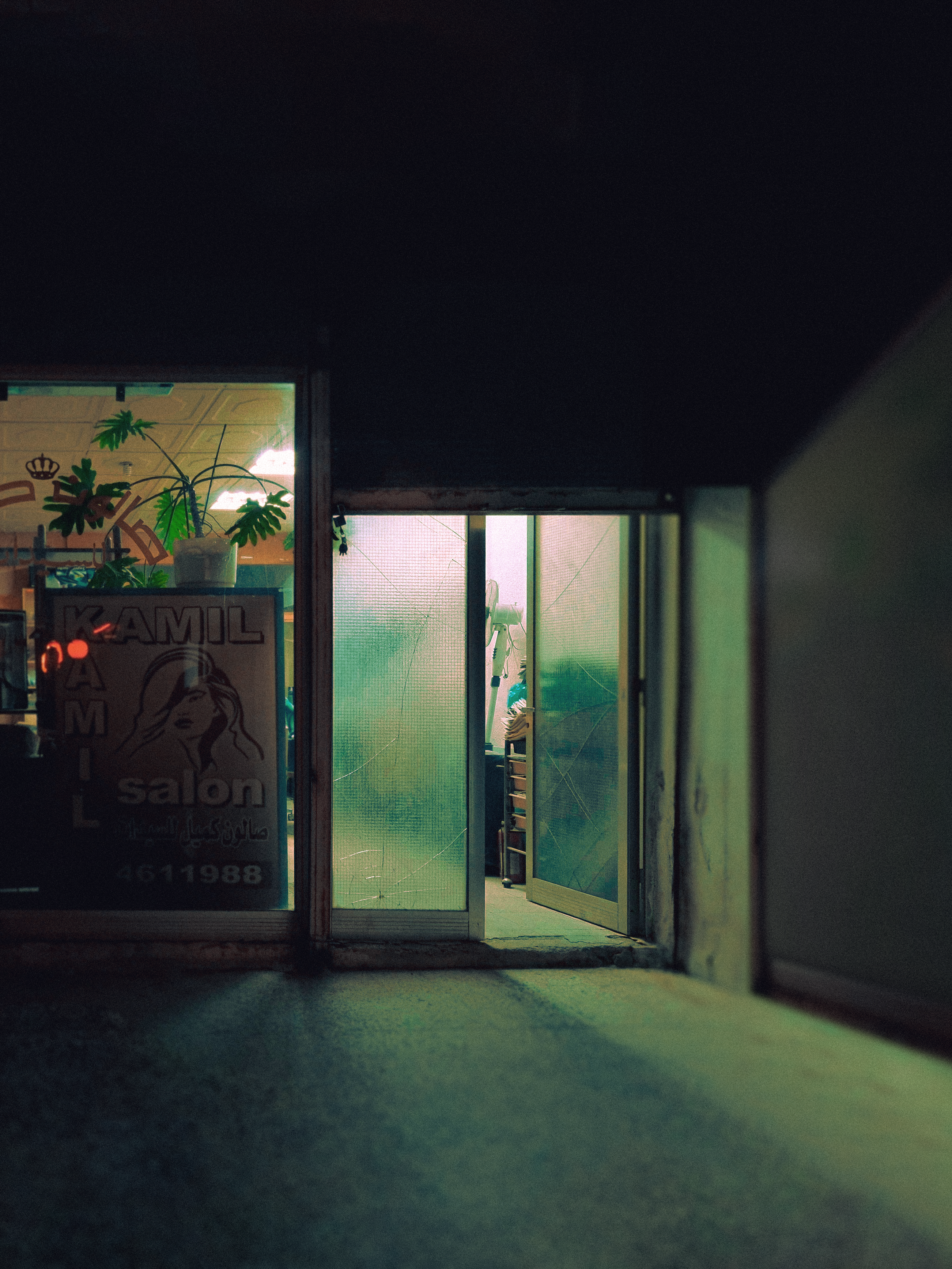 A dimly lit open door of a hair salon creating a moody atmosphere in the evening.