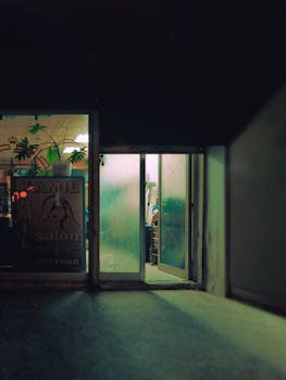 A dimly lit open door of a hair salon creating a moody atmosphere in the evening.