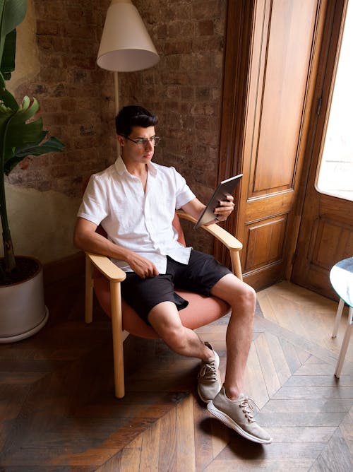 Man in White Shirt Sitting with Cellphone