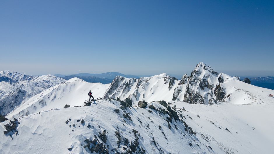 A breathtaking aerial view of a climber trekking snowy mountains in Miyada, Nagano, Japan.