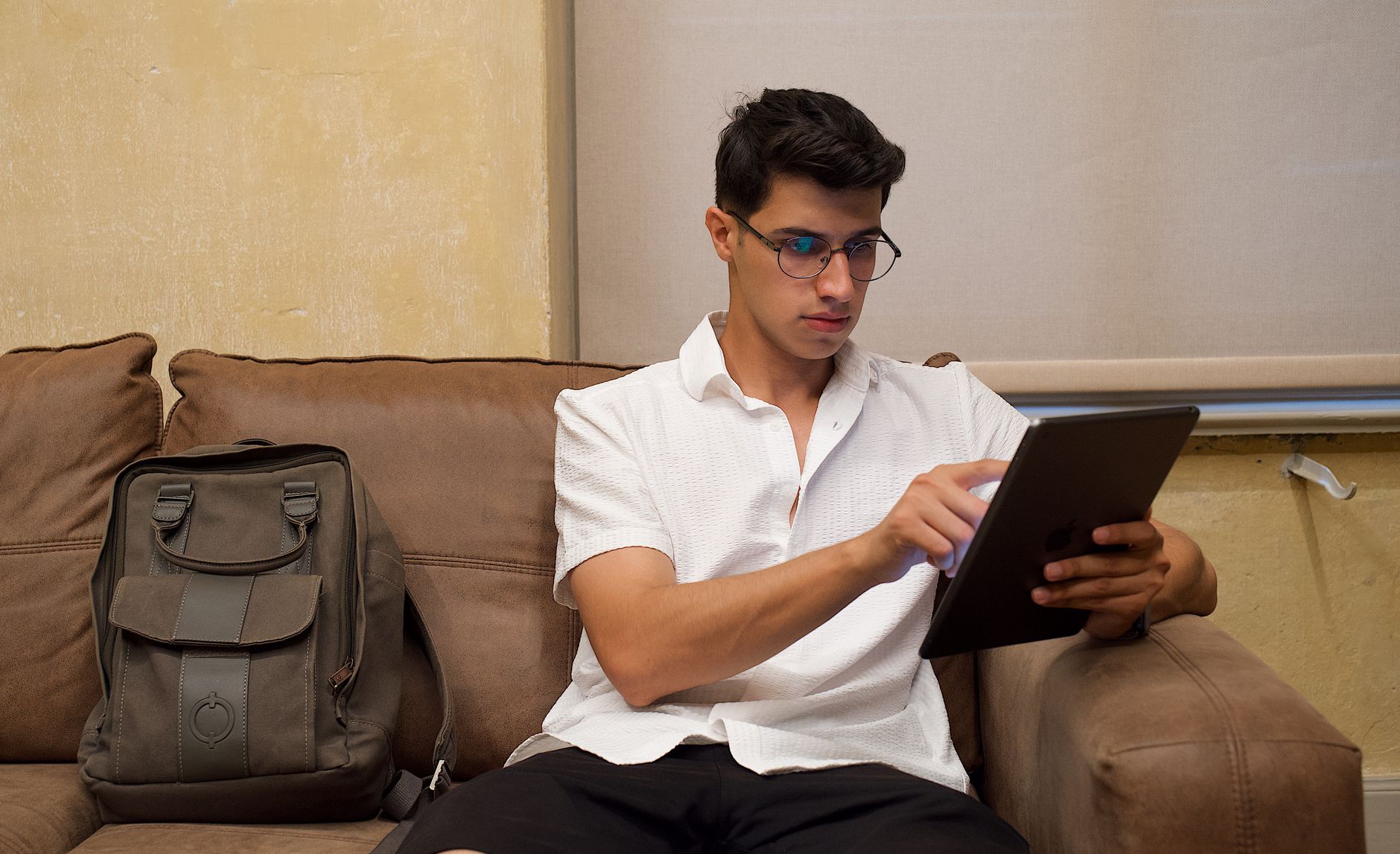 a gamer using a tablet to plan football plays, daylight desk with notes and headphones