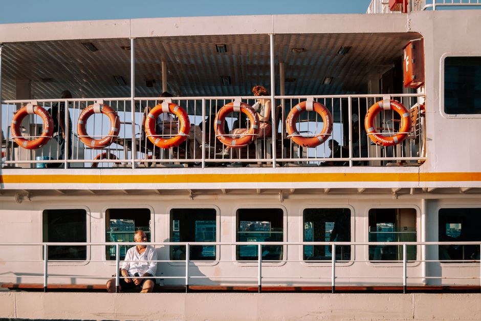 Passengers on a sunlit ferry in Turkey, featuring vibrant lifebuoys. Ideal for travel imagery.