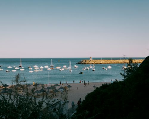 Free Scenic view of a calm beach with anchored boats and clear skies, perfect for summer leisure. Stock Photo