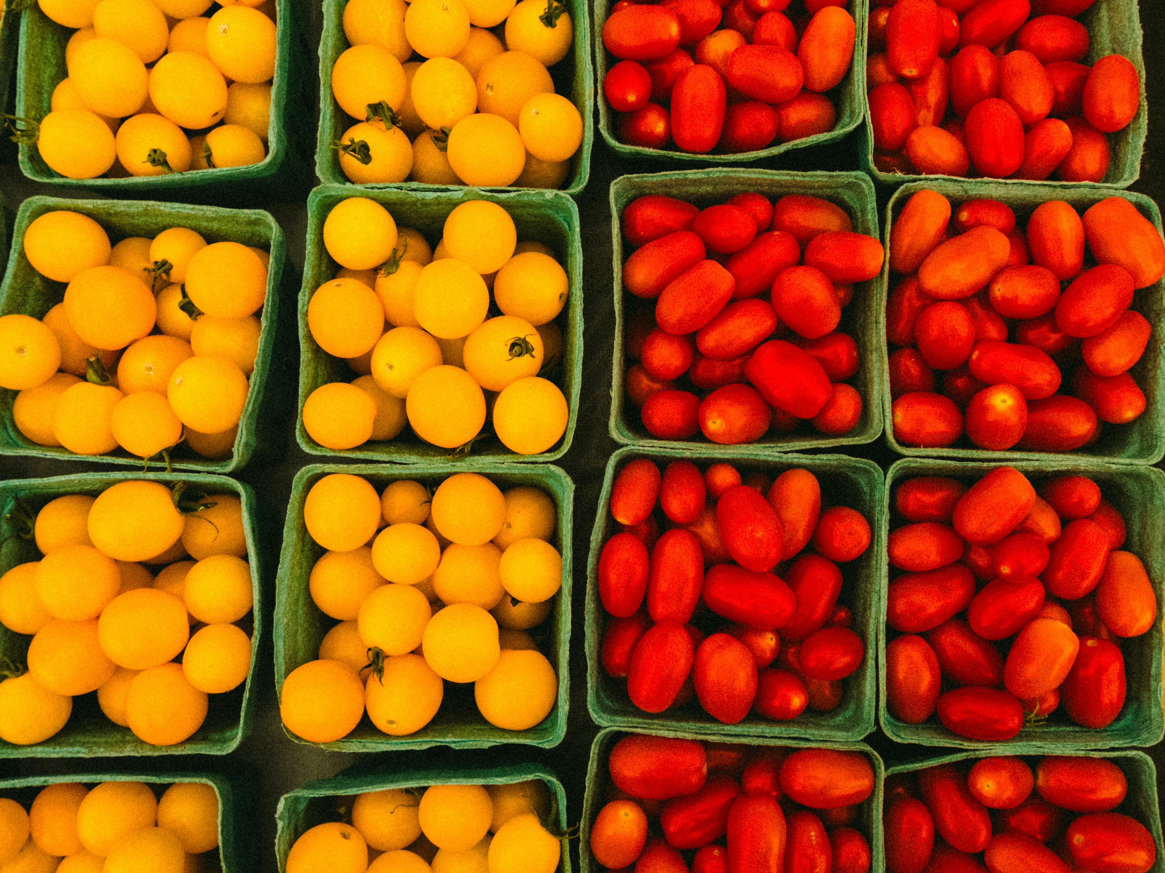 Top view of fresh yellow and red cherry tomatoes in baskets at a farmer's market.