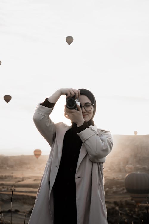 Woman Taking a Photo with Hot-Air Balloons Flying in the Background
