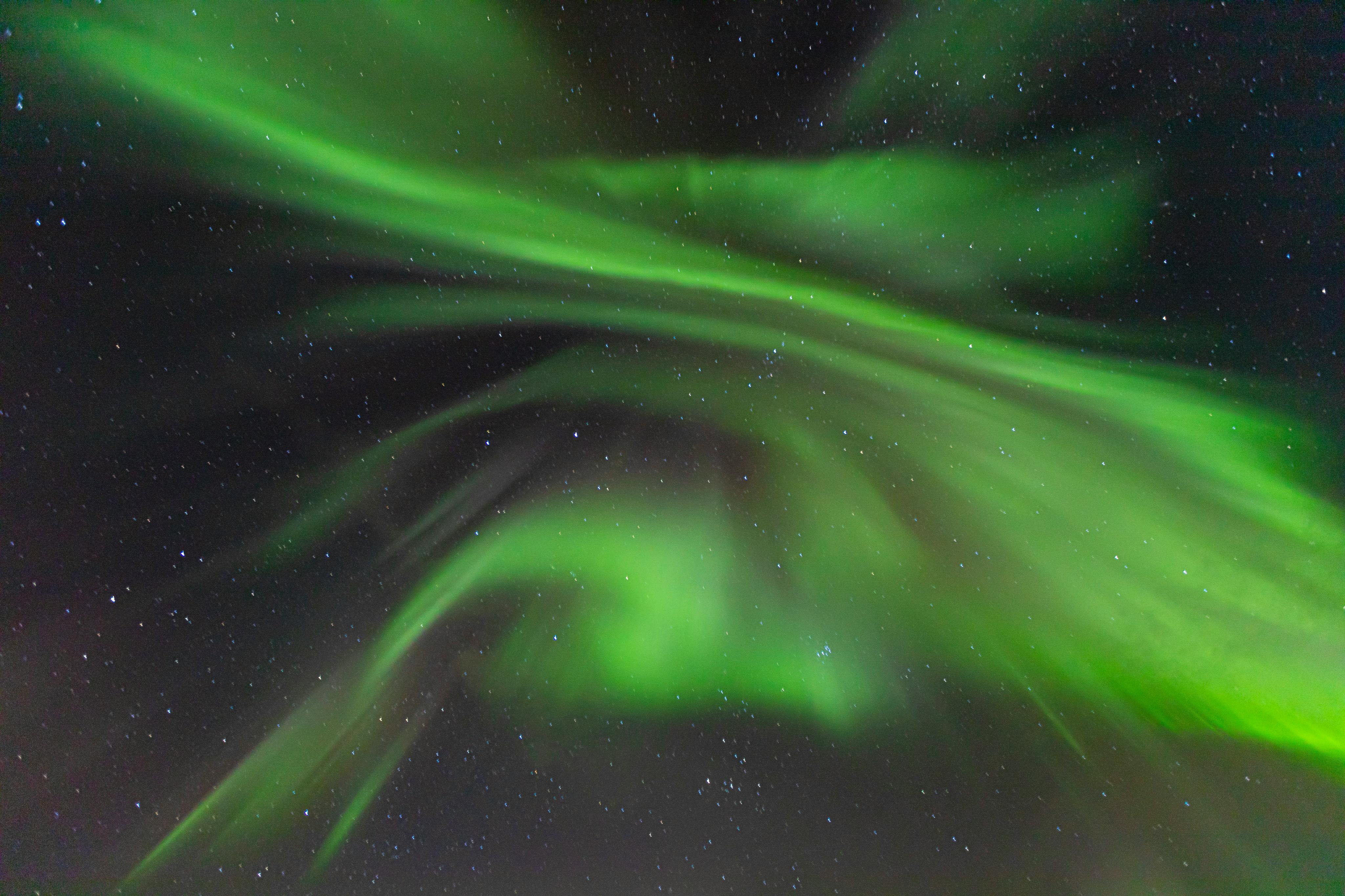 Green aurora borealis over a dark, starry sky