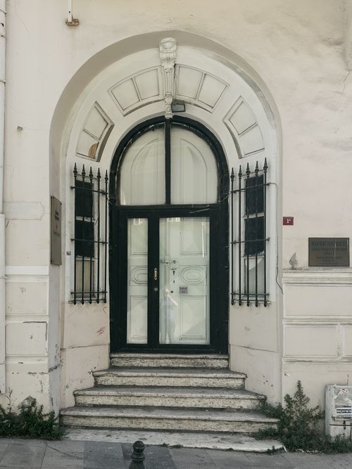 Free Classic arched doorway with decorative elements and stairs in an urban setting. Stock Photo