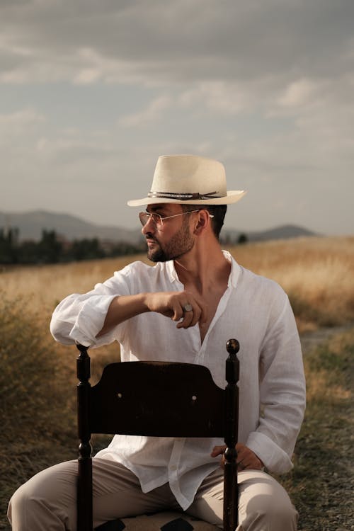 Elegant Man Sitting on a Chair on a Rural Field 