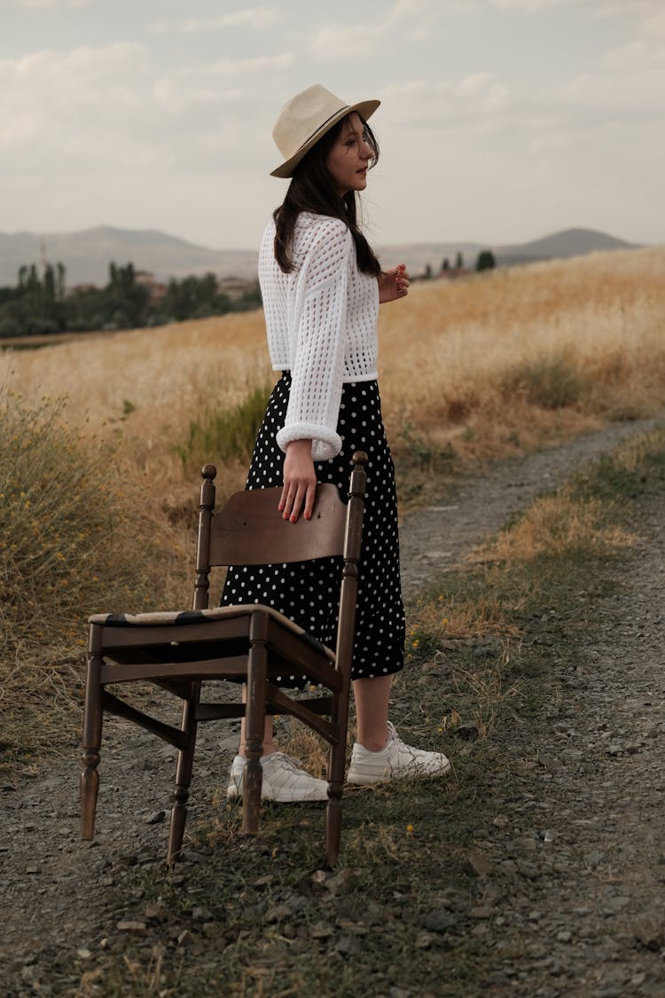 Woman Pulling Chair On Dirt Road