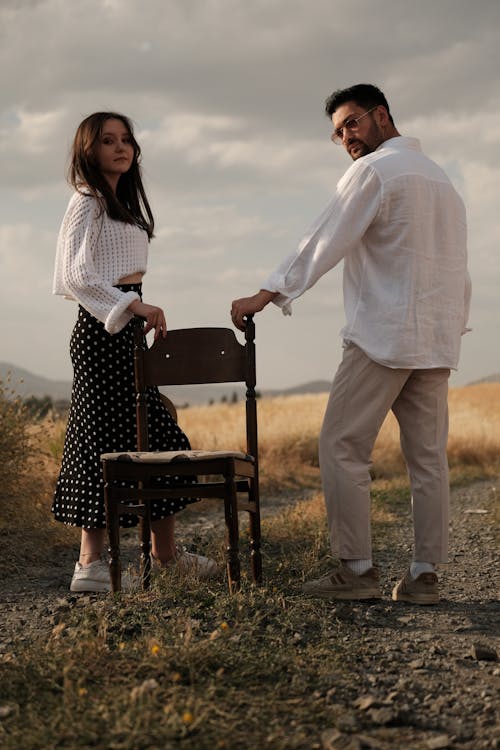 Couple Standing on Country Road and Holding Chair