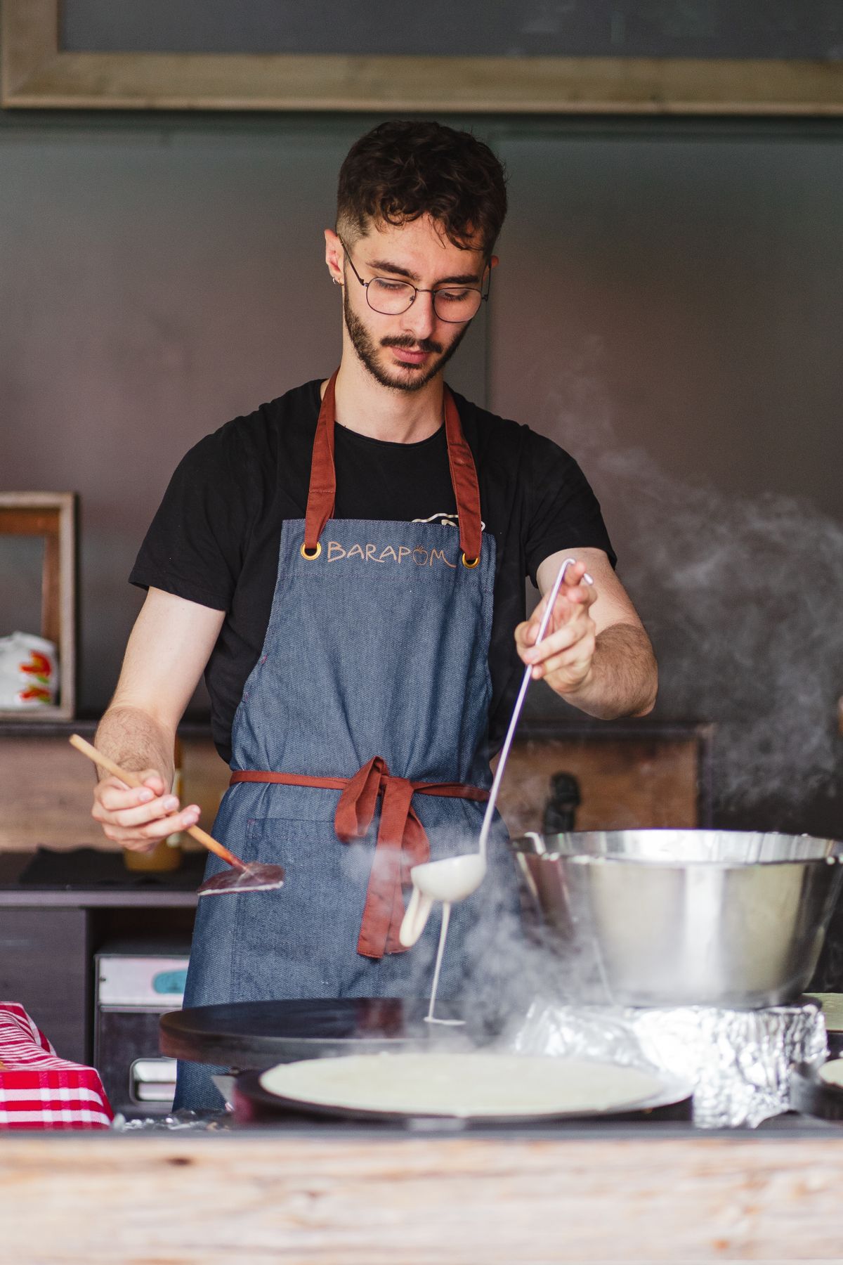 Cook actively warming a thin crepe in a pan before turning it