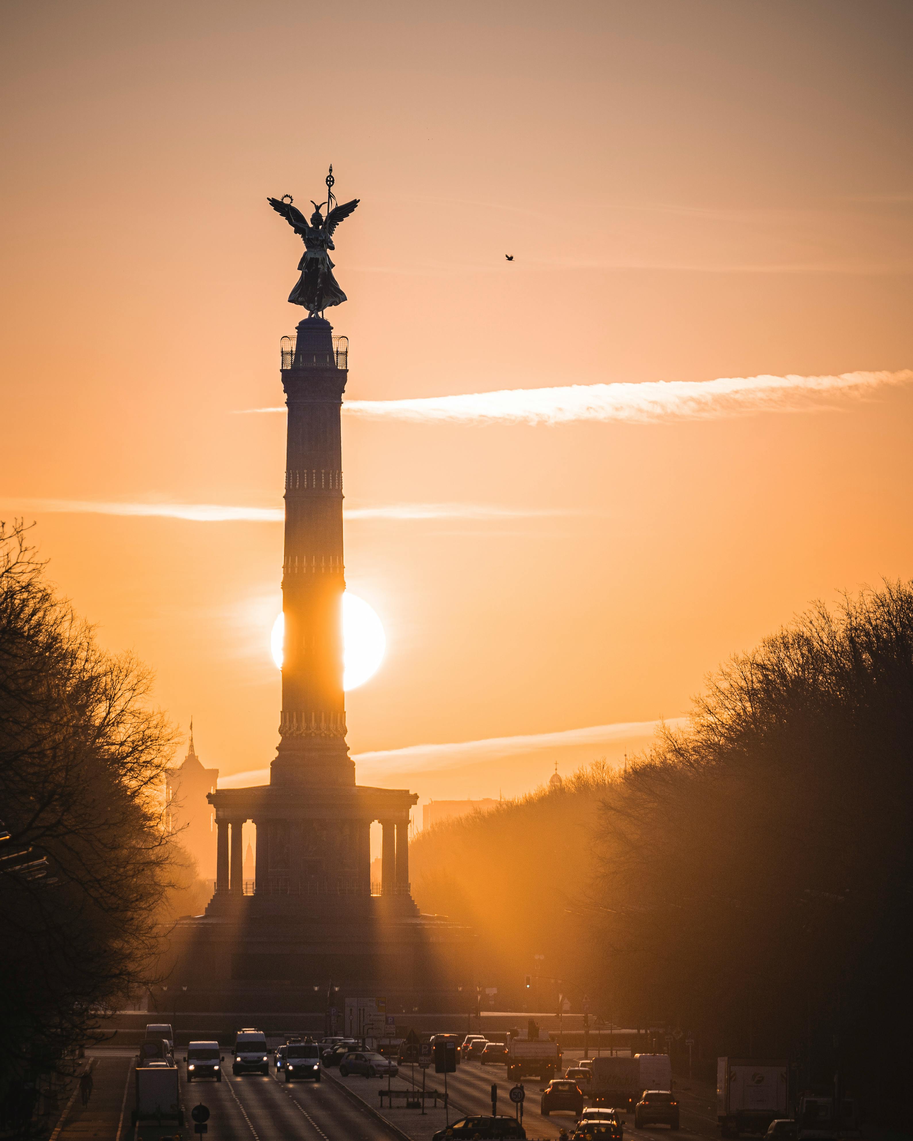 Stunning sunset view of the Berlin Victory Column with a dramatic yellow sky.