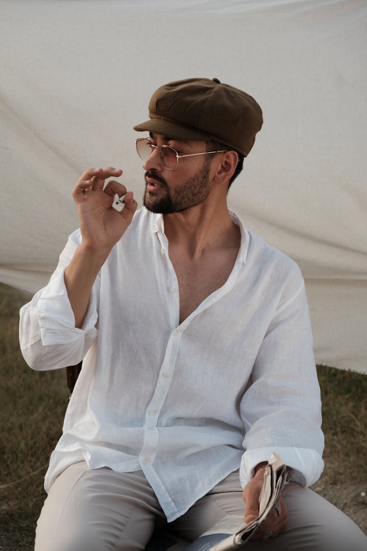 A Man Sitting Outside And Smoking A Cigarette 