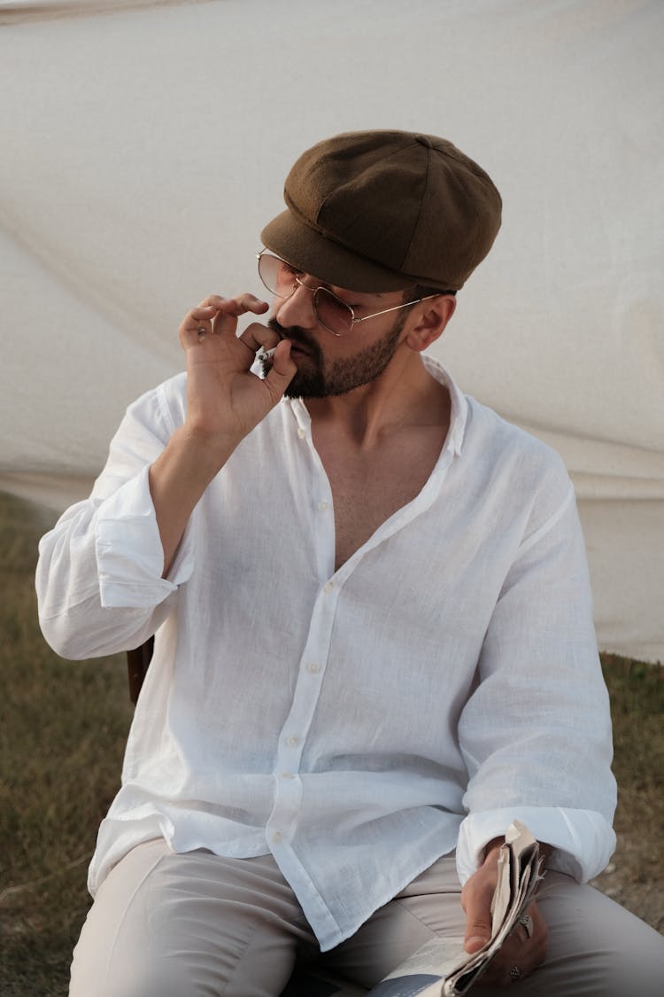 A Man Sitting Outside And Smoking A Cigarette 